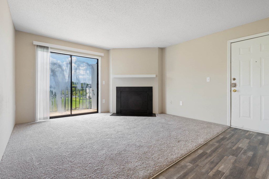 an empty living room with a fireplace and sliding glass doors at Village 1373, Greensboro