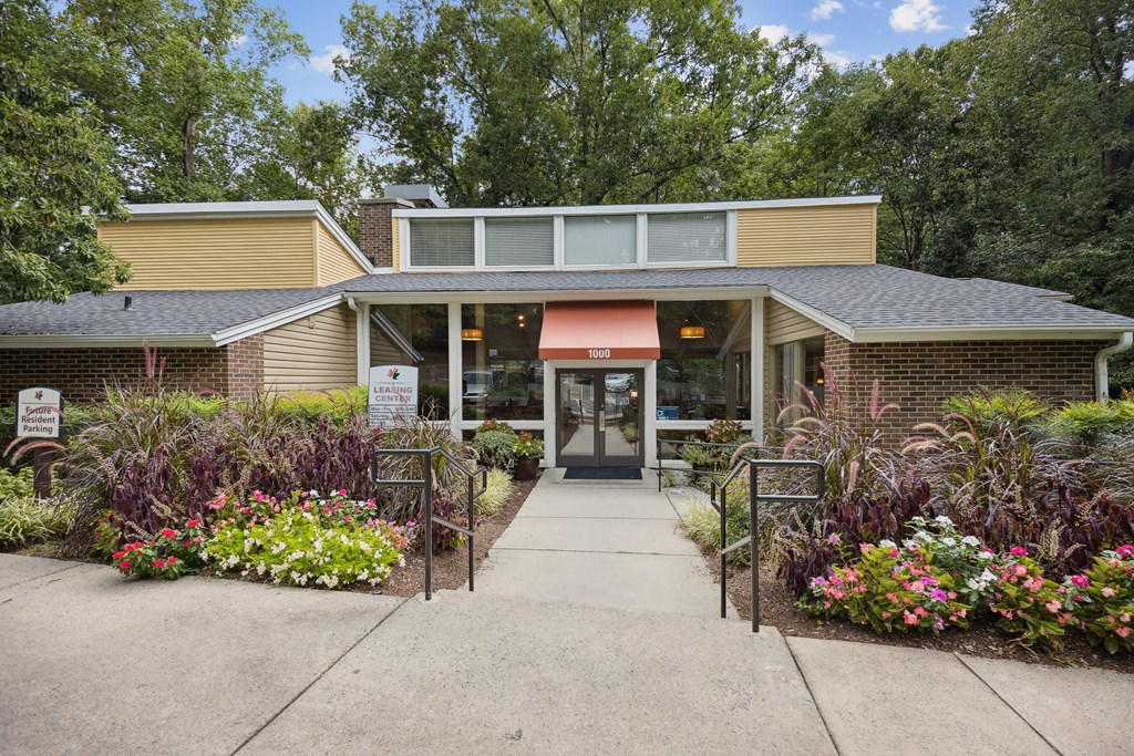 a brick building with a red awning and a flower garden in front of it
