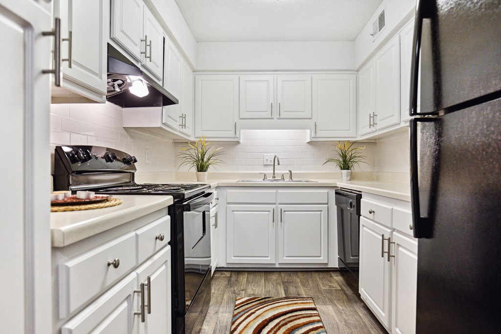 a kitchen with white cabinets and black appliances
