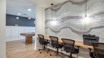 A conference room with a marble wallpaper and a printer on the desk.