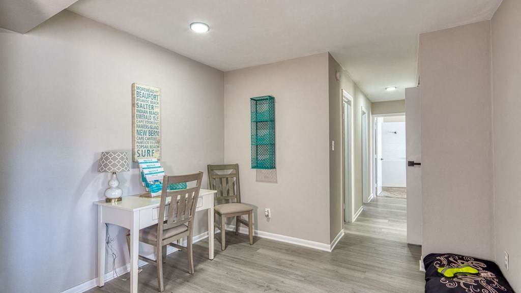 a dining room with a table and chairs and a hallway with a door at Bayville Apartments, Virginia Beach