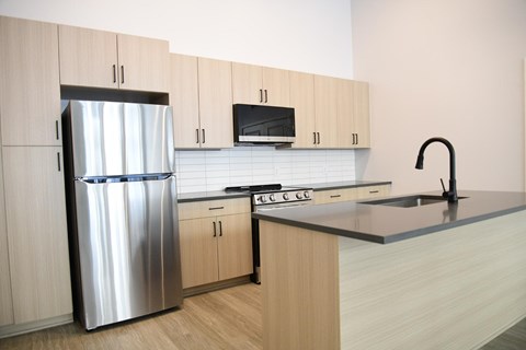 A modern kitchen with a stainless steel refrigerator and wooden cabinets.