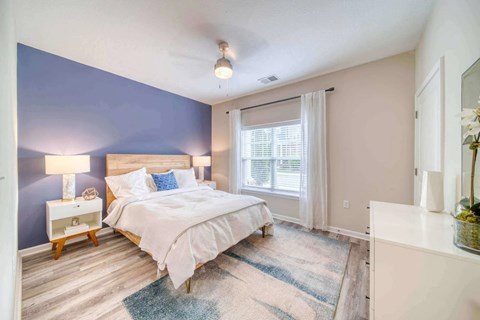 A bedroom with a bed, nightstand, and window.