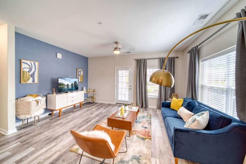 A living room with a blue couch and a wooden floor.