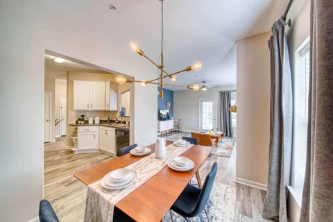 A dining room with a table set for two and a kitchen in the background.