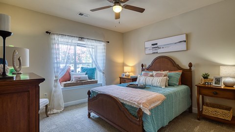 A bedroom with a bed, nightstand, and window.