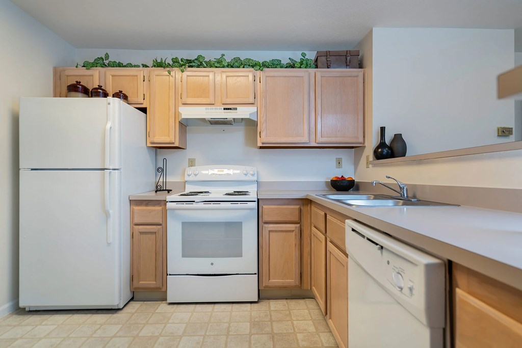 A kitchen with a white refrigerator, white oven, and white dishwasher.at Camden Place, Ohio