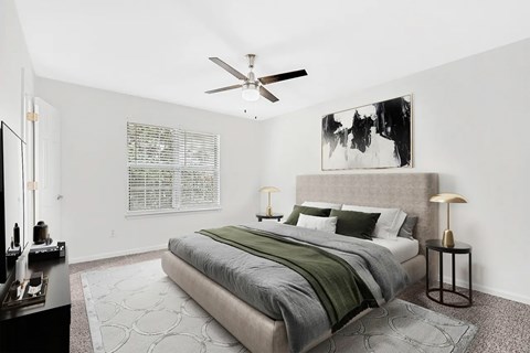 A bedroom with a large bed and a ceiling fan.