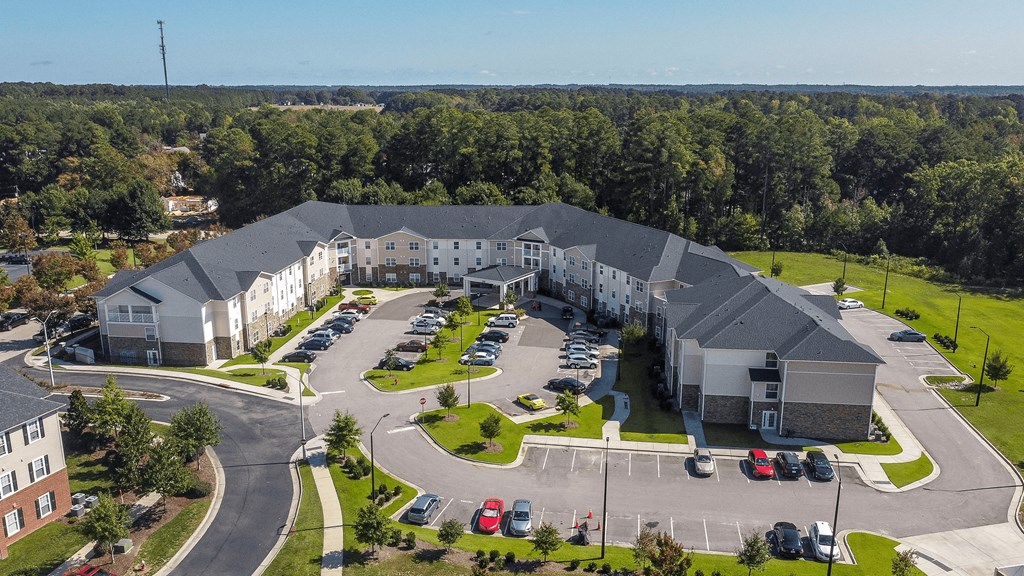 an aerial view of an apartment building with parking lot and cars
