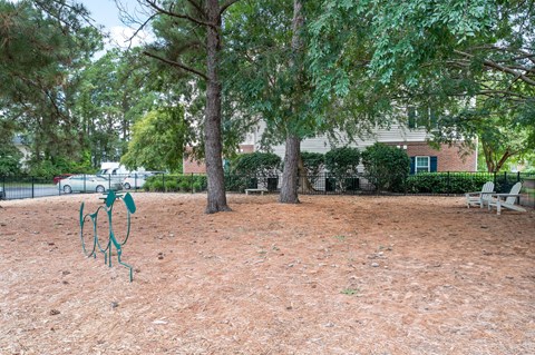 A playground with a swing set in the middle of a dirt area at Litchfield Oaks Apartments in Pawleys Island, South Carolina
