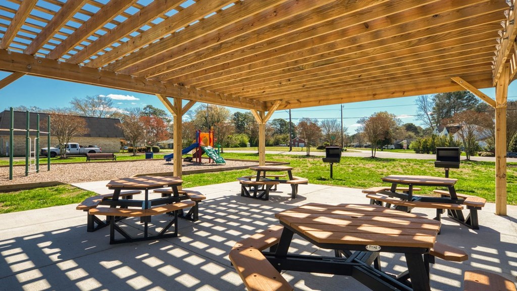 two picnic tables under a wooden pavilion in a park  at Bayville Apartments, Virginia Beach