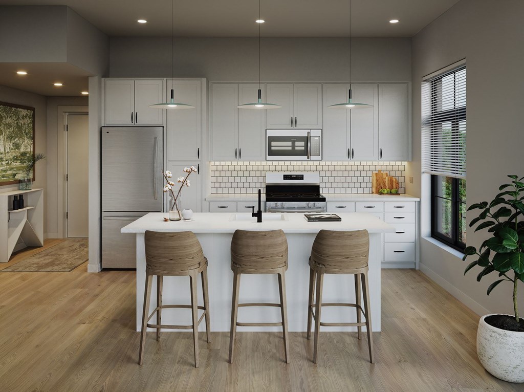 A modern kitchen with a white island and bar stools.at Aviator Lofts, Newport News