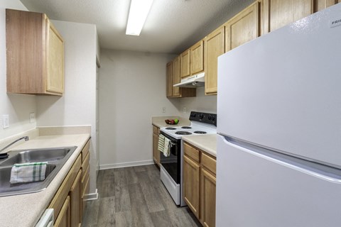 A kitchen with a white refrigerator, wooden cabinets, and a stove top oven.