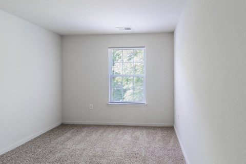 A room with a carpeted floor and a window.