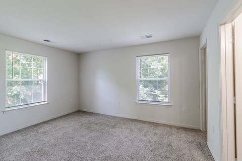 A room with two windows and carpeted floor.