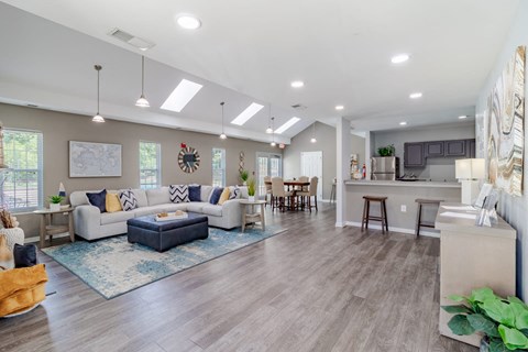A spacious living room with a grey sofa set and a blue rug.