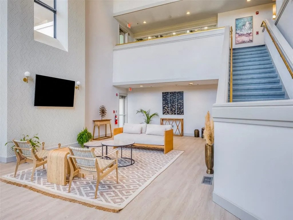 a living room with a couch and chairs and a staircase