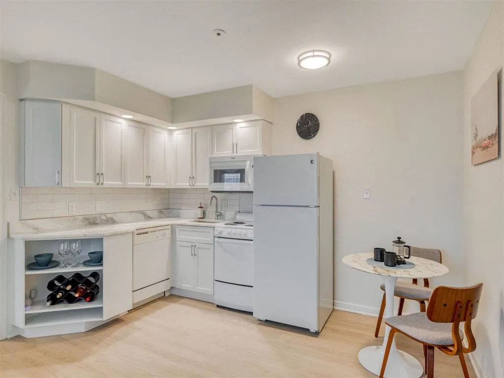 a kitchen with white appliances and a small table with chairs