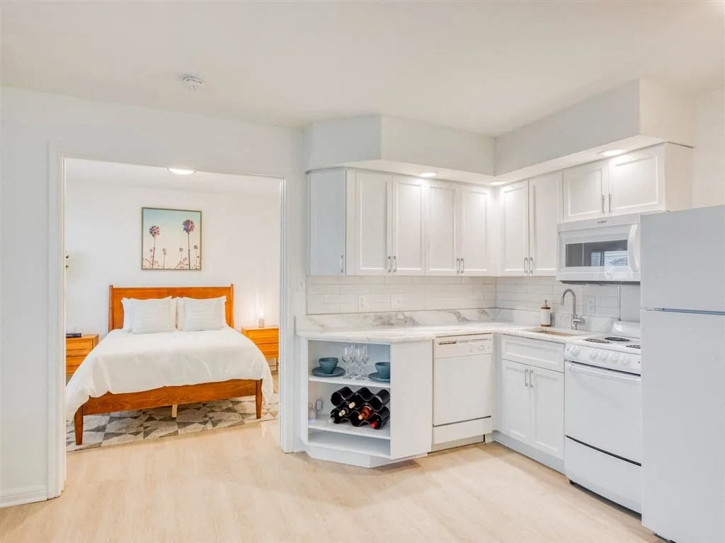 a bedroom with a bed and a kitchen with white cabinets