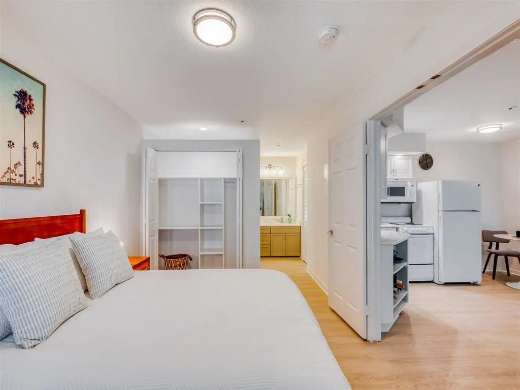 a bedroom with a bed and a kitchen with a refrigerator