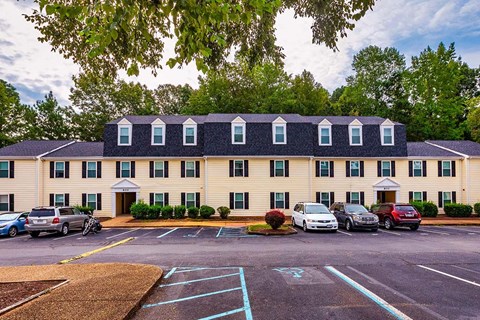 A parking lot in front of a building with cars parked.