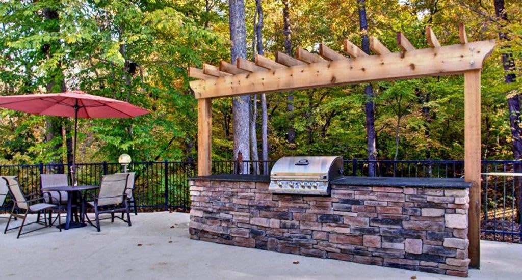 a patio with a barbecue grill and a table and chairs