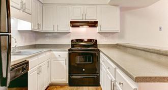 a kitchen with white cabinets and black appliances