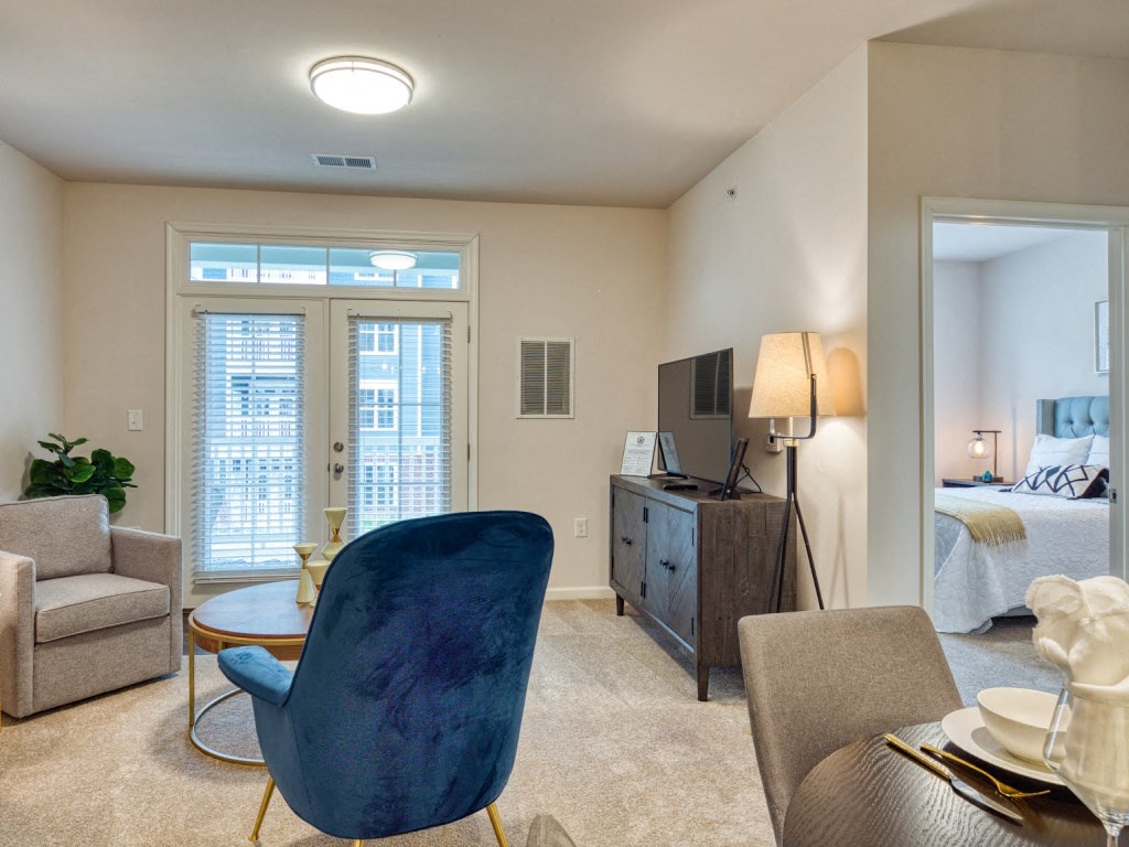 a living room with a blue chair and a door to a bedroom