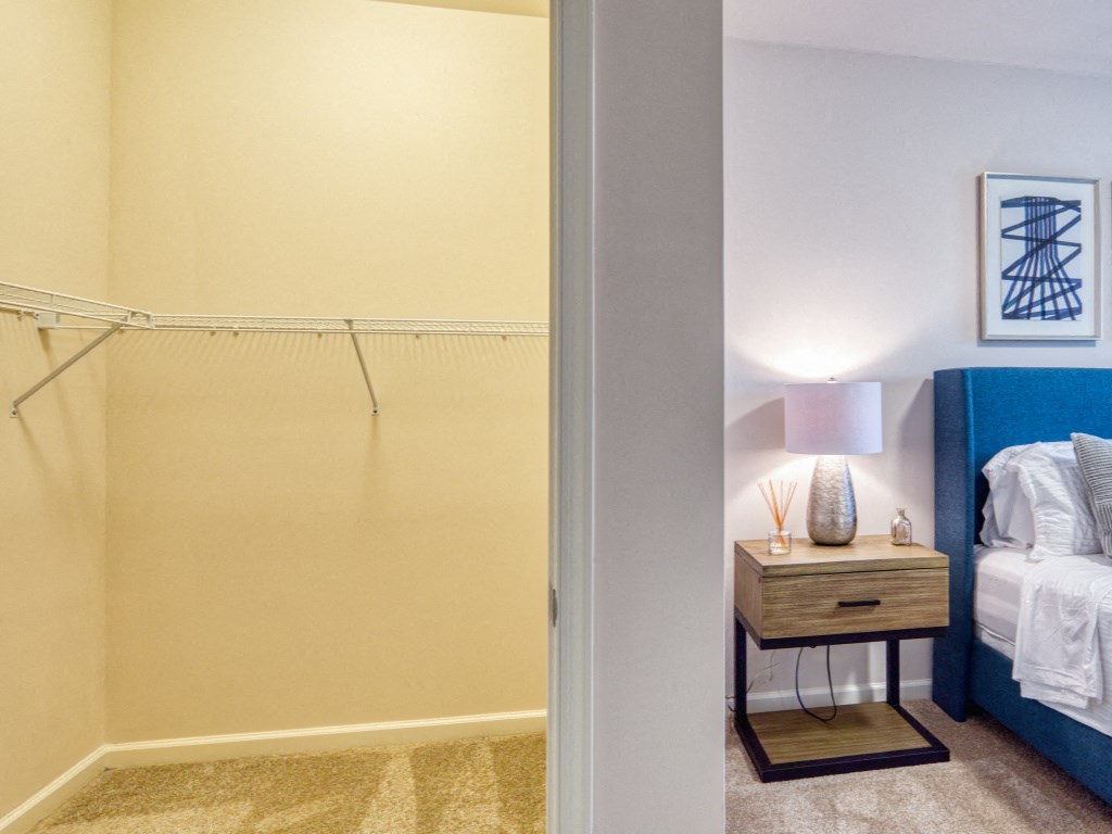 a bedroom with a closet and a bed and a nightstand with a lamp