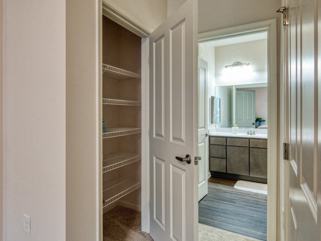 a walk in closet in a home with a door open to a bathroom