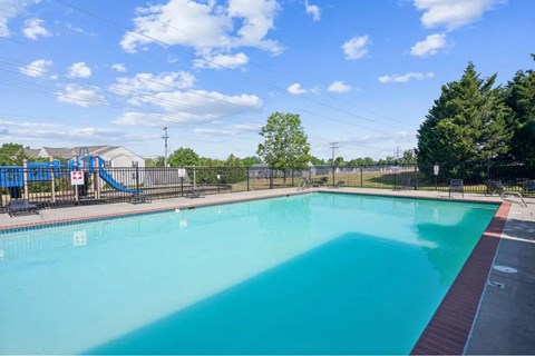 A large outdoor swimming pool with a slide in the background.
