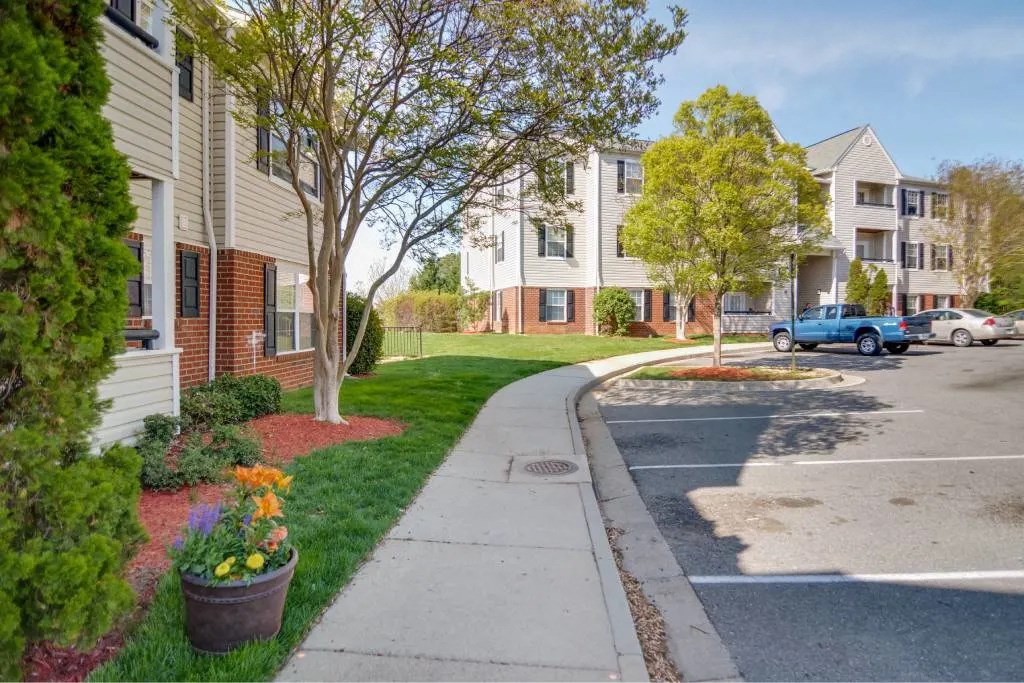 A view of a street with apartment buildings and cars.