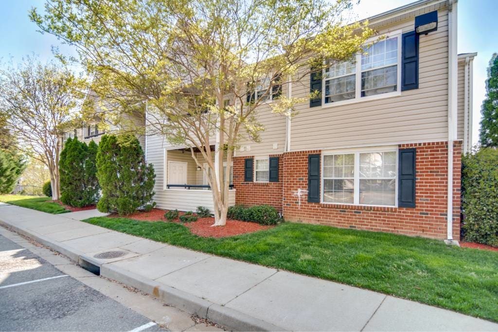 A tree with yellow leaves is in front of a house.