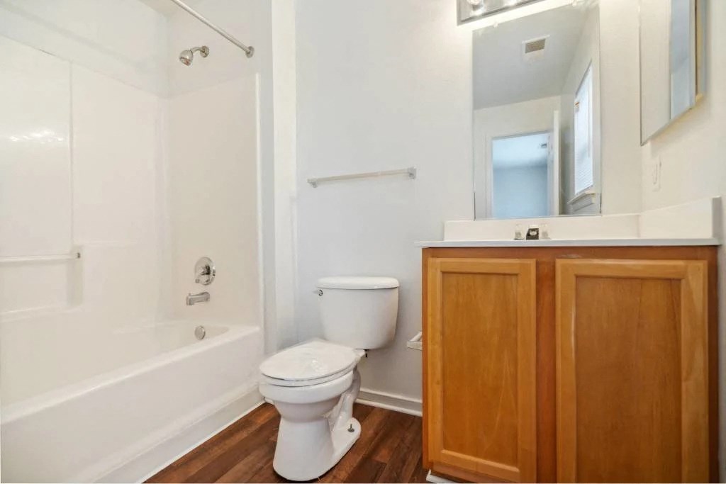 A white toilet sits in a bathroom next to a white bathtub.