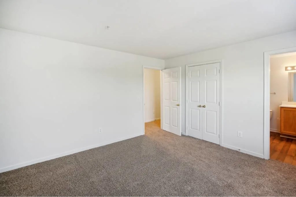 A room with white walls and a grey carpet.
