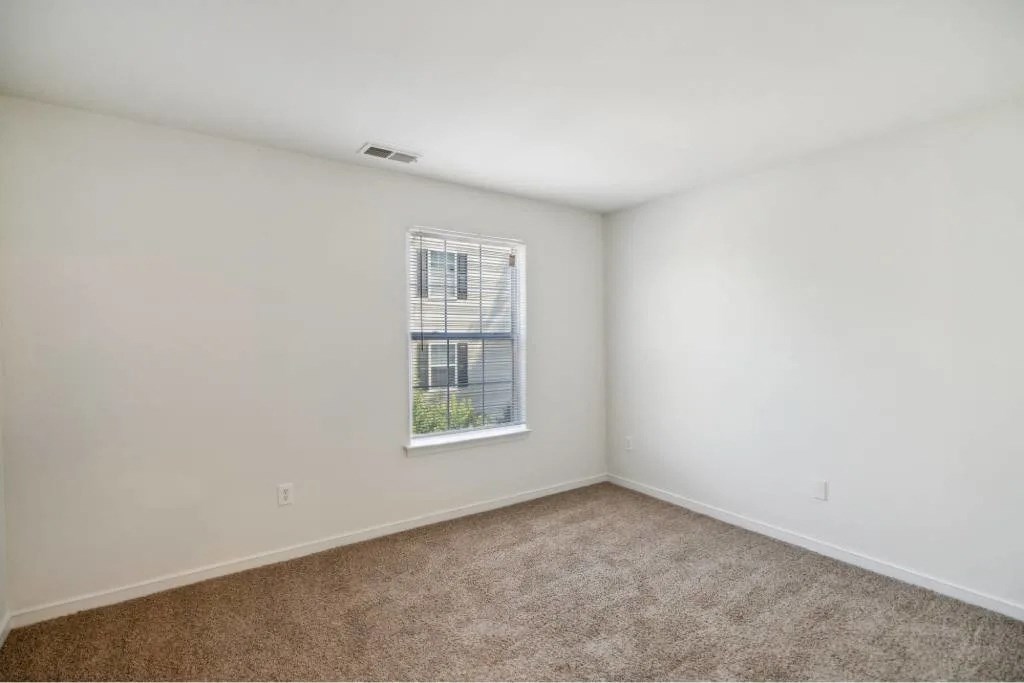 A room with a window and carpeted floor.