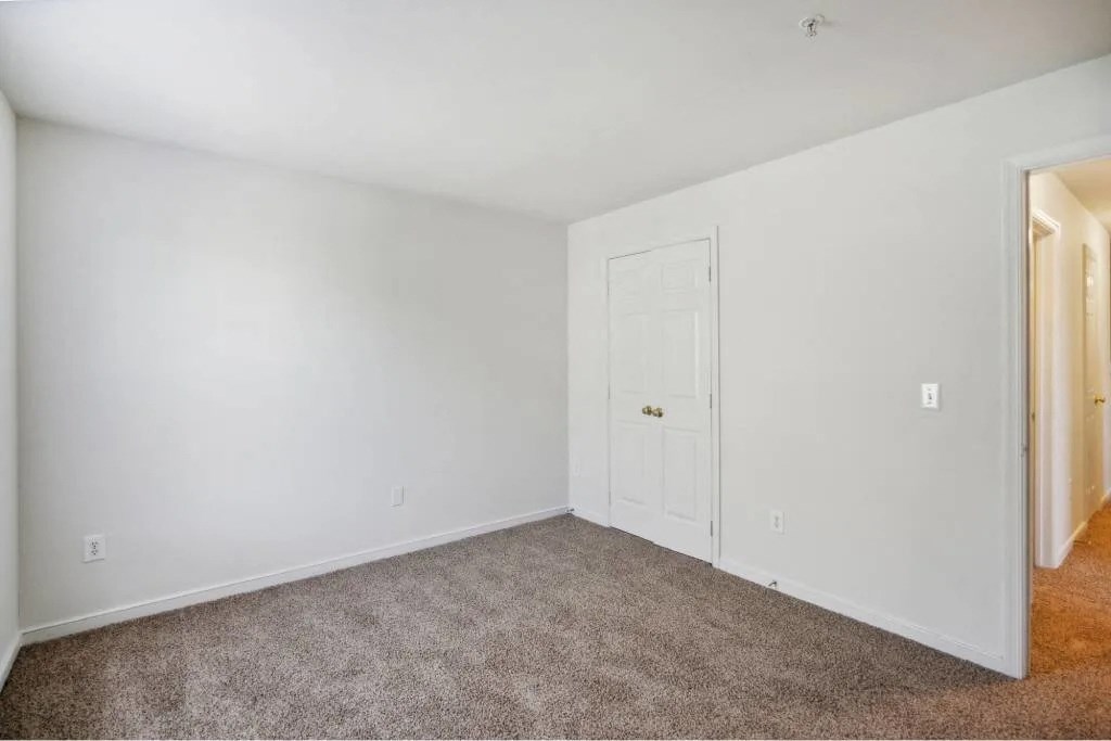 A room with a carpeted floor and a white door.