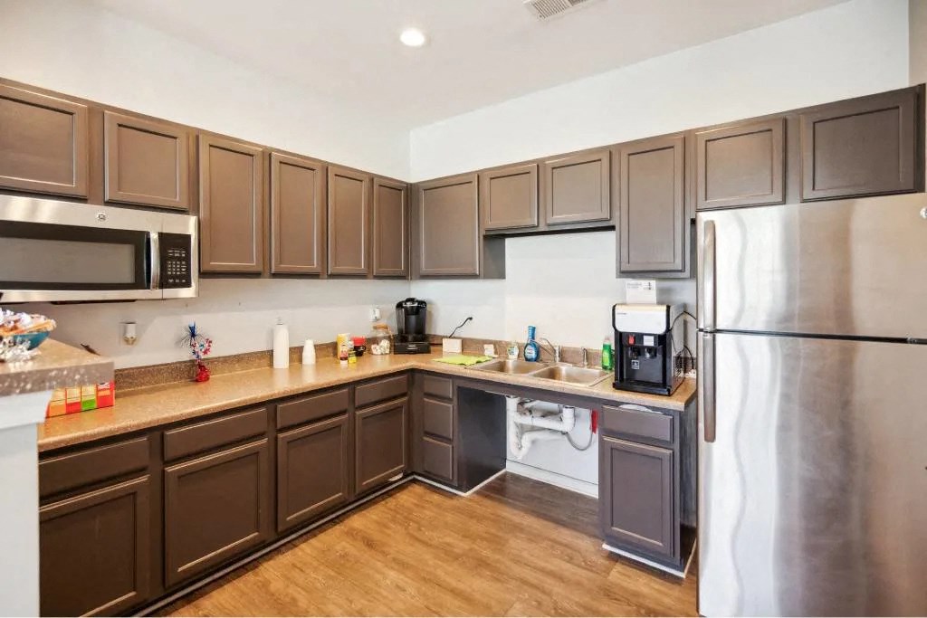 A kitchen with brown cabinets and a stainless steel refrigerator.
