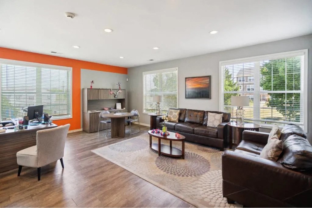 A living room with a brown leather couch and a wooden floor.