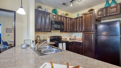 A kitchen with brown cabinets and a black refrigerator.