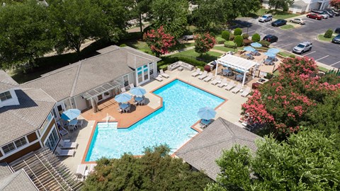 A large swimming pool surrounded by trees and a building.
