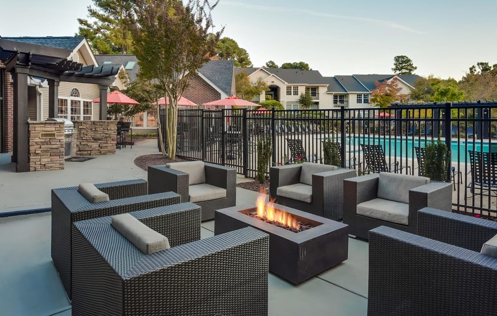 a patio with chairs and a fire pit near a pool at Midtown Crossing, Raleigh