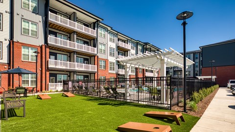 A sunny day at a modern apartment complex with a green lawn and picnic tables.