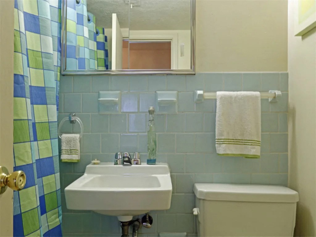 a bathroom with a sink and a toilet and a mirror at Gates of West Bay, Norfolk