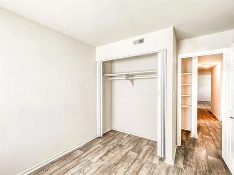 an empty bedroom with a closet and a mirrored closet door