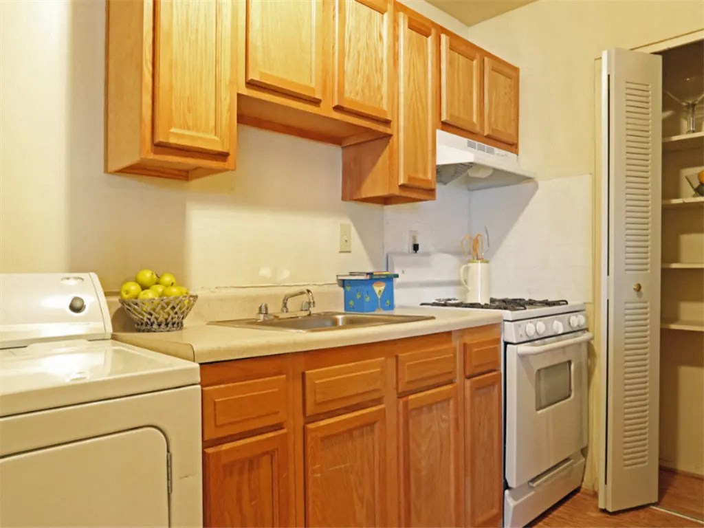 a kitchen with white appliances and wooden cabinets at Gates of West Bay, Virginia, 23503