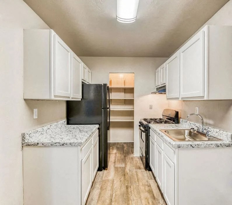 a kitchen with white cabinets and a black refrigerator at Gates of West Bay, Norfolk Virginia