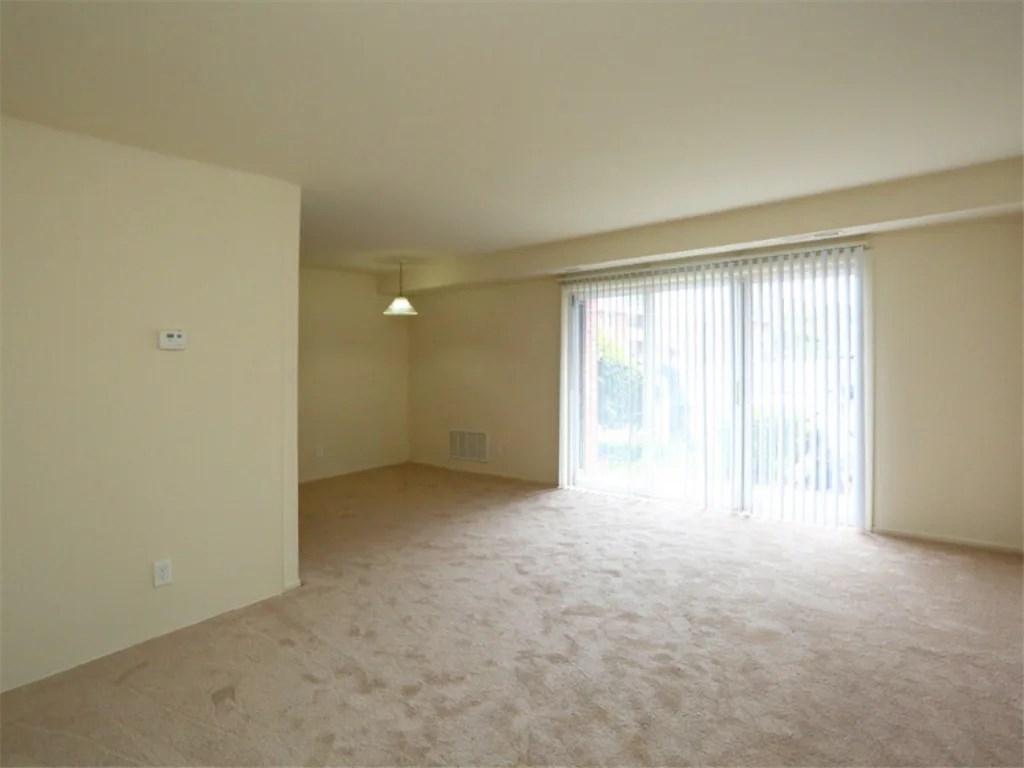 an empty living room with a sliding glass door to a patio at Gates of West Bay, Virginia