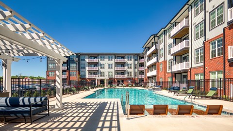 A pool area with sun loungers and a white canopy.