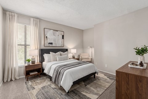 A bedroom with a large bed and a wooden nightstand.